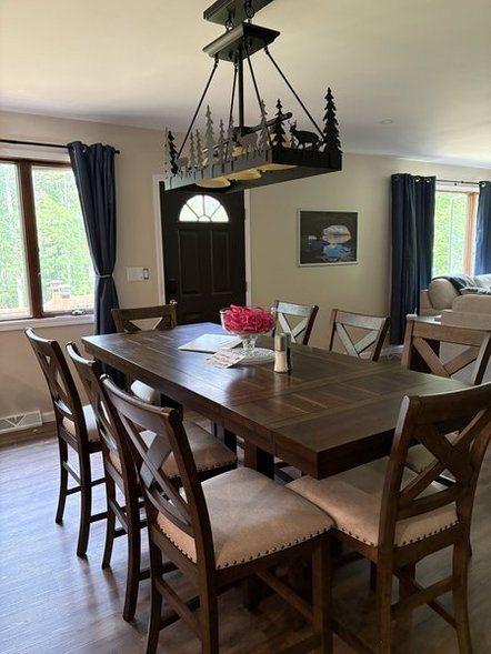 Large dining table under a pine-and-deer chandelier